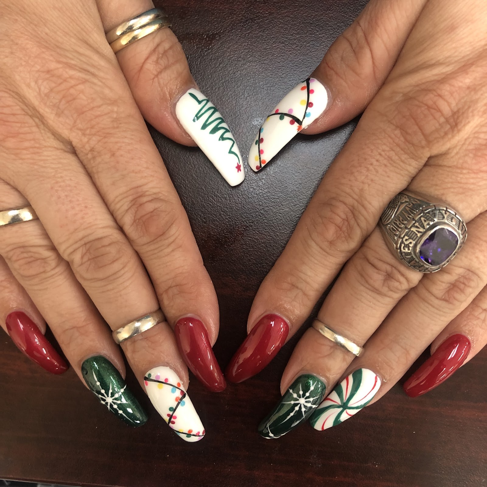 Festive red, green and white hand-painted holiday nail art with snowflakes and candy cane designs