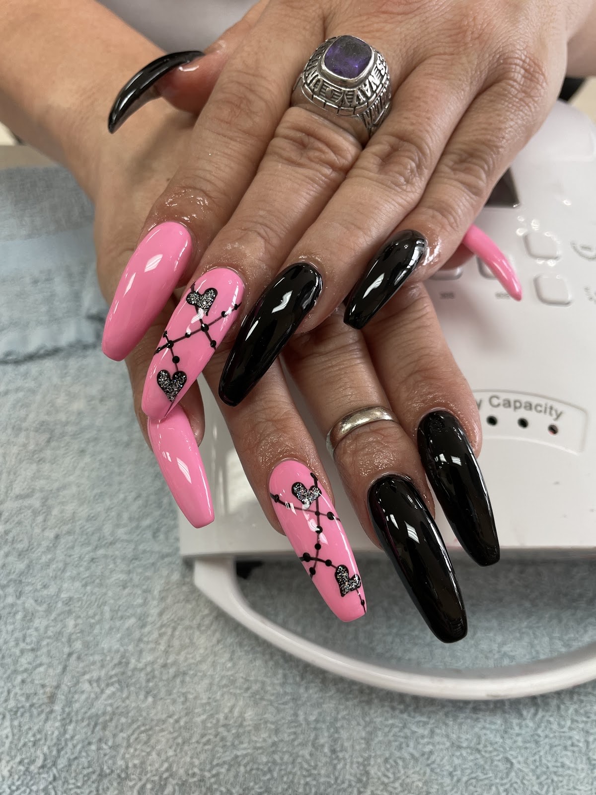 Glossy pink and black coffin nails with hand-painted heart details at Twinkle Nails & Spa